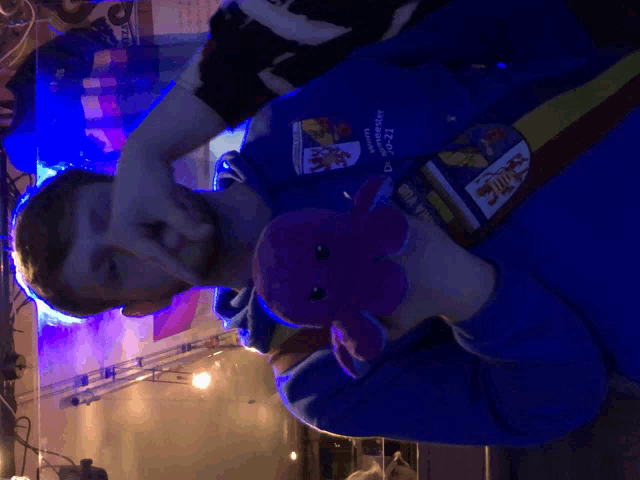 a man holding a stuffed animal with a blue shirt that says ' tsc ' on the front