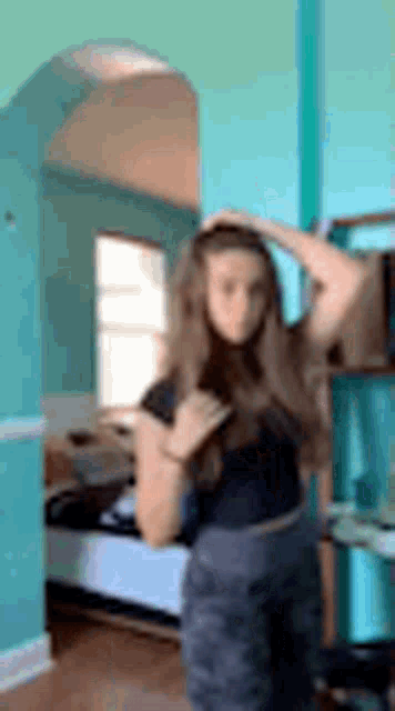 a woman is standing in a room with a blue wall .