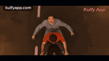 a man is sitting on another man 's back .