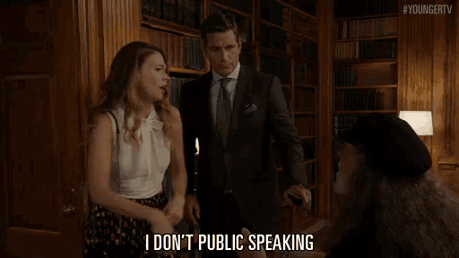 a man in a suit and tie stands next to a woman in a white top and says i don t public speaking