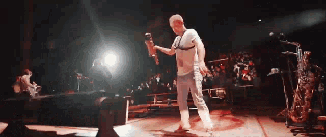 a man in a white shirt is dancing on stage
