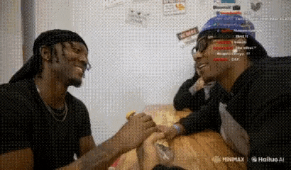 two men are sitting at a table holding hands and laughing .