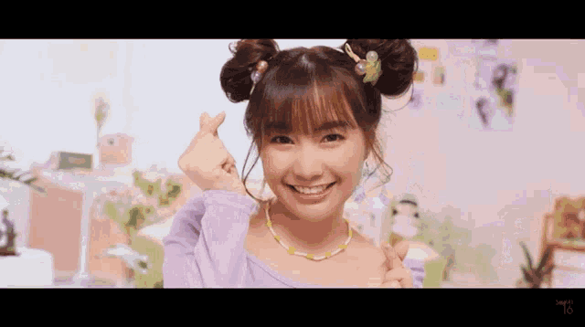 a girl with pigtails and a necklace is making a heart shape with her hands