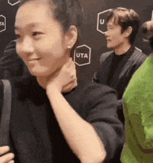 a woman holds her neck in front of a wall that says uta on it