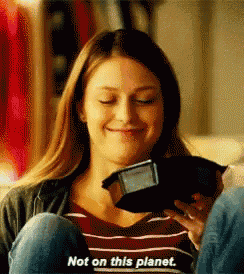 a woman is sitting on a couch holding a purse and smiling while saying not on this planet .