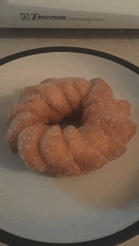 a donut on a plate with a emerson microwave oven behind it