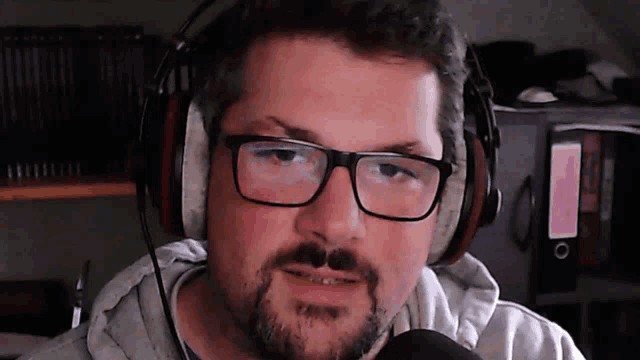 a man with glasses and a beard wearing headphones and a microphone