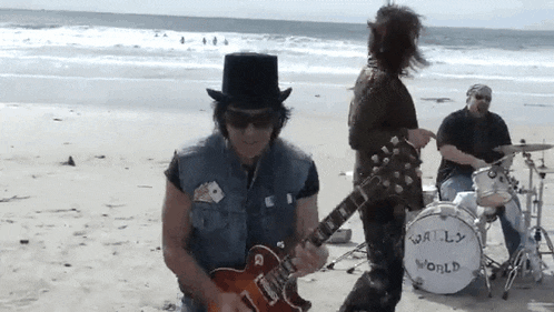 a man playing a guitar on the beach with a drum that says world