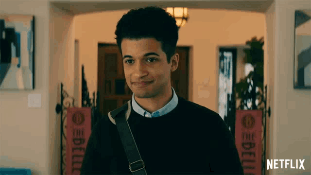a man in a black sweater is smiling in front of a netflix sign