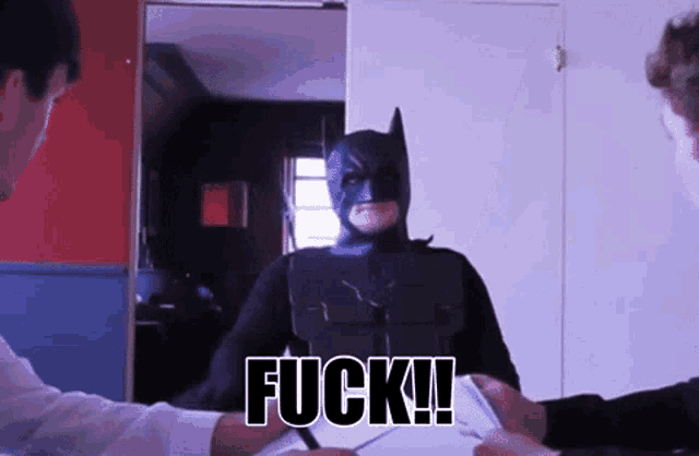 a man in a batman costume has the word fuck written on his face