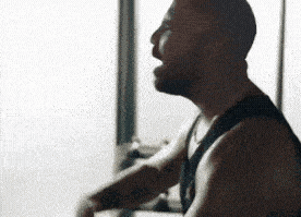 a man with a beard is singing into a microphone while standing in front of a window .