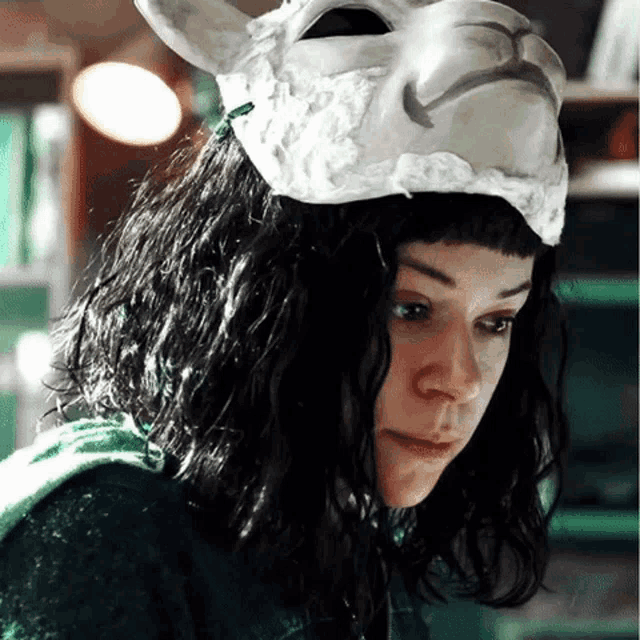 a woman wearing a white mask on her head looks down