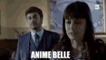 a man and a woman are standing next to each other in a room and the woman is looking at the man .