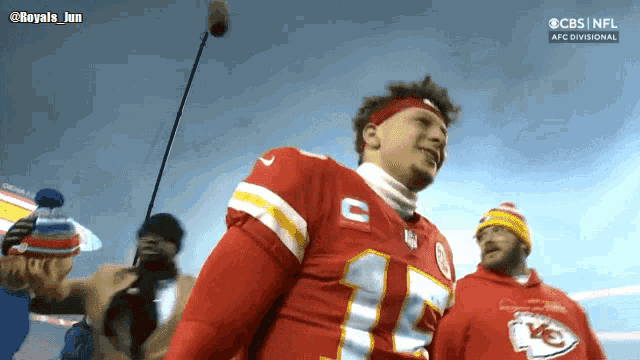 a man in a chiefs jersey stands in front of a cbs nfl logo