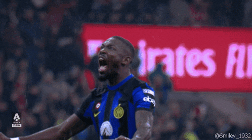 a soccer player screams in front of an emirates ad