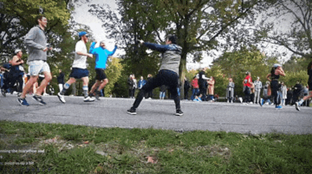 a group of people are running in a park and one of them is wearing a blue hat
