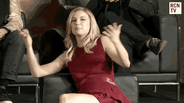 a woman in a red dress sits in a chair with rcn tv written on the bottom right