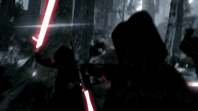 a man is holding two red lightsabers in the dark