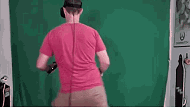 a man wearing a virtual reality headset is playing a video game in front of a green screen .