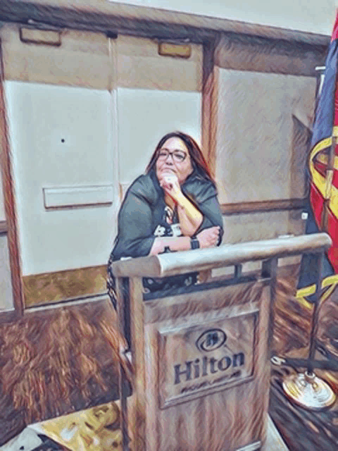 a woman stands at a podium that says hilton