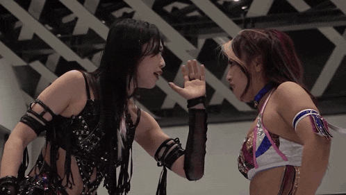two women wrestling in a ring with one wearing a blue choker that says ' a ' on it