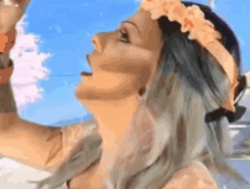 a woman is wearing a flower crown on her head and looking up .