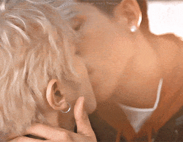 two men are kissing each other and one has earrings on