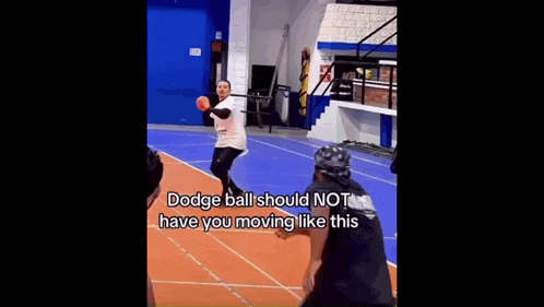 a man wearing a helmet is playing dodgeball on a court while another man watches .