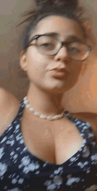 a woman wearing glasses and a pearl necklace is taking a selfie