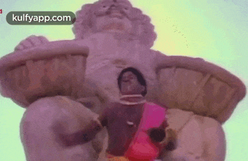 a man is sitting in front of a statue of a lion holding a basket .