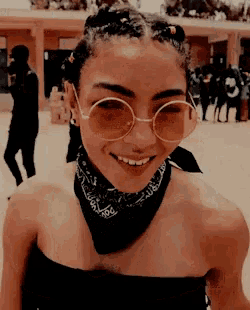a woman wearing sunglasses and a bandana smiles