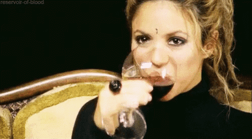 a woman is drinking a glass of red wine from a glass .