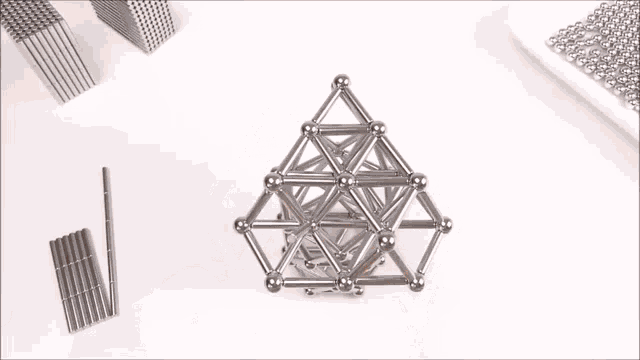 a person is playing with a pyramid made of magnetic balls .