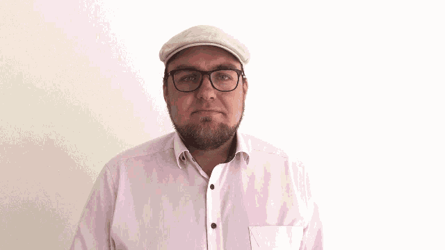 a man wearing glasses and a pink shirt is pointing