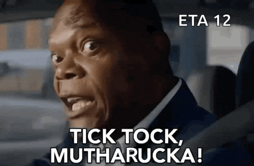 a man in a suit is driving a car and saying tick tock , mutharucka !