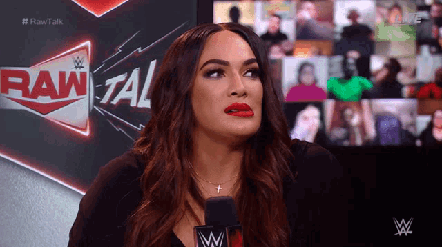 a woman with red lipstick is talking into a microphone in front of a sign that says raw talk
