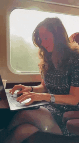 a woman is using a laptop on a train