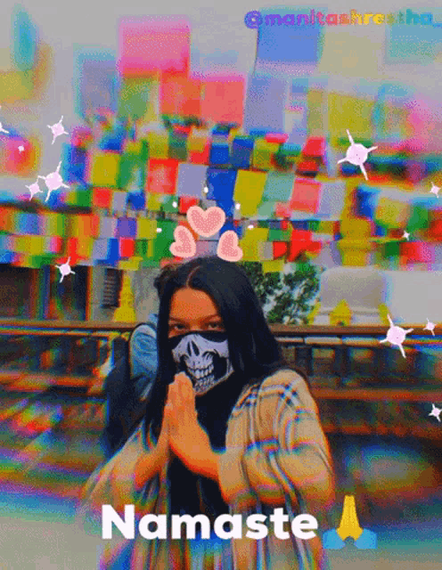 a woman wearing a skull face mask prays in front of a colorful background with the words namaste below her