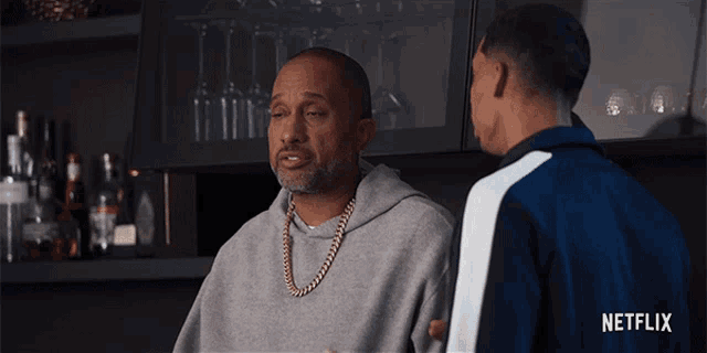 a man in a grey hoodie talks to another man in a netflix ad