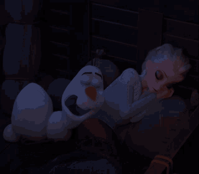 a cartoon character sleeping next to an olaf doll