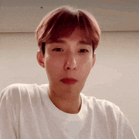 a young man with pink hair is wearing a white t-shirt .