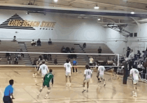 a volleyball game is being played in a gym with a long beach state sign on the wall