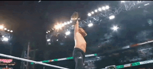 a man in a wrestling ring holding a championship belt