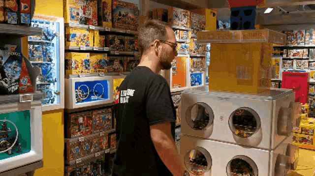 a man wearing a black shirt that says loading black is standing in a toy store