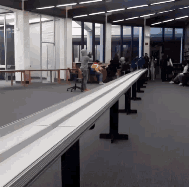 a long row of tables in a library with people sitting at them