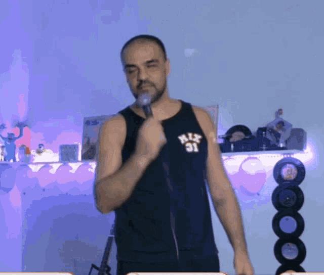 a man wearing a black tank top with the number 31 on it holds a microphone