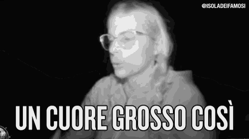 a woman wearing glasses is talking in a black and white photo with the words `` un cuore grosso cosi '' .