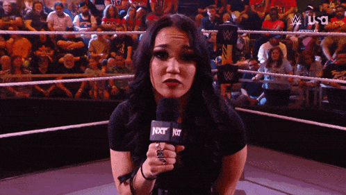 a woman is holding a microphone that says nxt