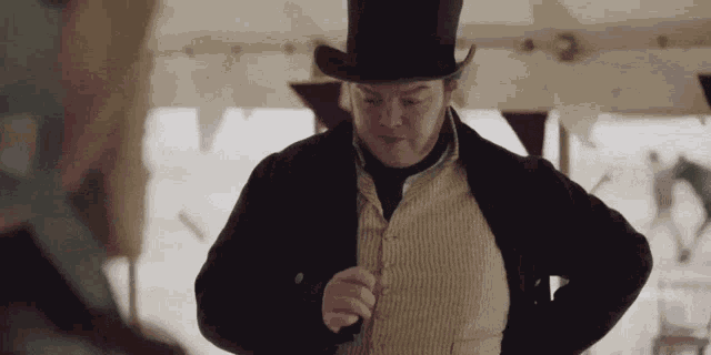 a man wearing a top hat and a black jacket is standing in front of a tent