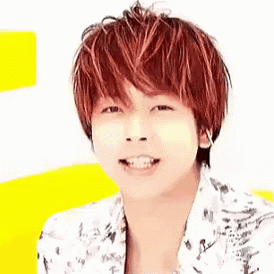 a young man with red hair and a white shirt is smiling and looking at the camera .